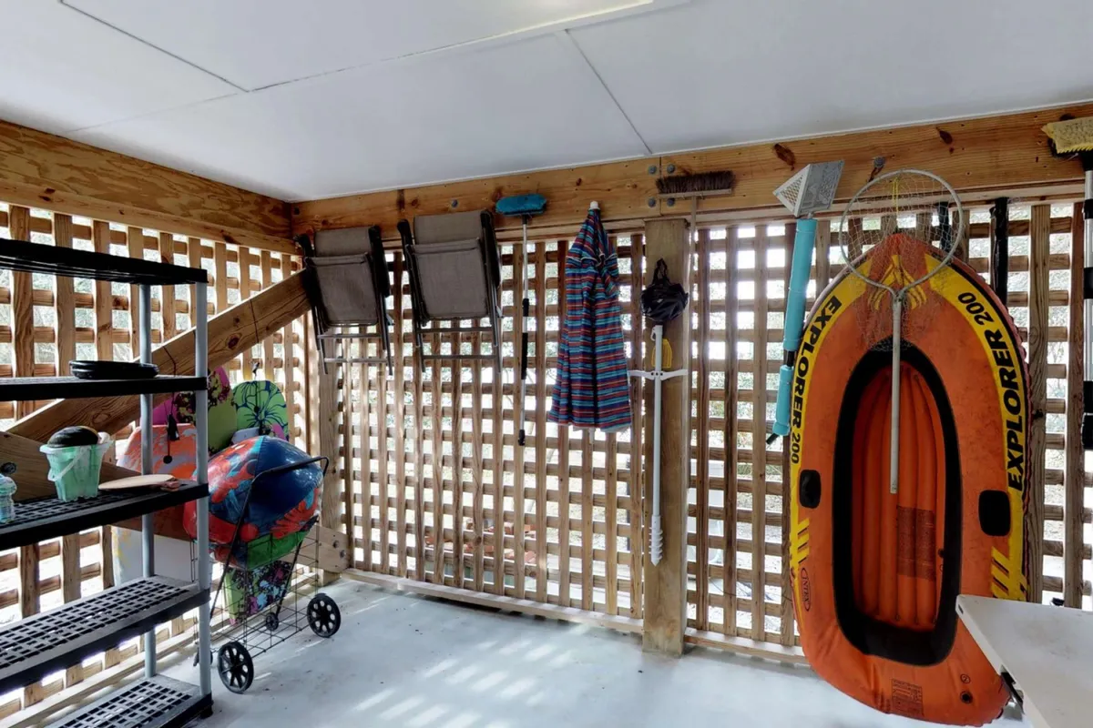 A well-organized storage area containing an orange inflatable kayak, colorful beach gear, and shelves with storage bins. The space is ready for easy access to recreational equipment and demonstrates practical, thoughtful organization.