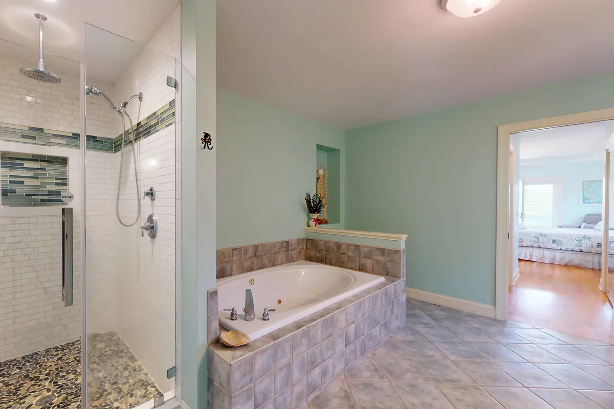 A serene bathroom featuring a jacuzzi tub and separate shower area, with tile flooring and soft lighting that creates a calming spa-like atmosphere. The space feels luxurious and perfectly suited for unwinding at the end of the day.